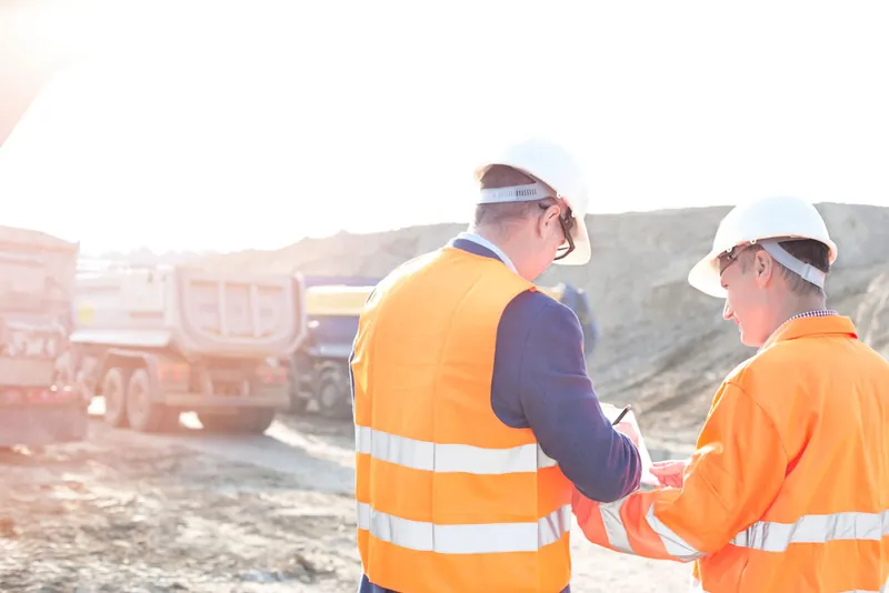 Engineers in hard hats reviewing plans on a job site