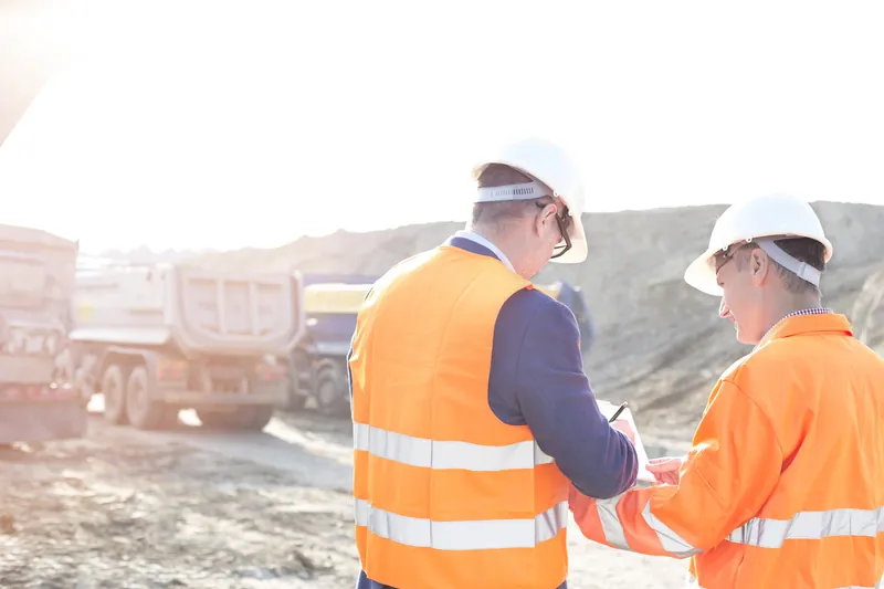 Engineers in hard hats reviewing plans on a job site