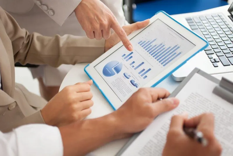 Hands reviewing charts on a tablet and paper
